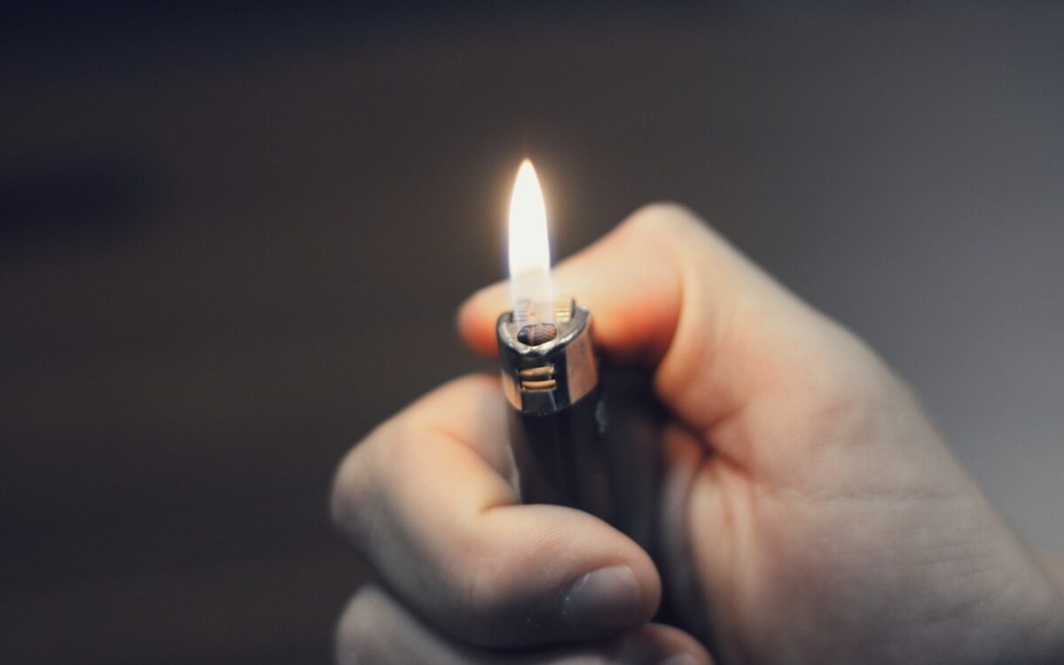 Eine Person hält ein Feuerzeug in der Hand Eine Person hält ein Feuerzeug in der Hand